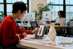 Usuario tocando la pantalla PROLED XDR del nuevo MacBook Pro en una oficina